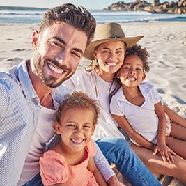 Family smiling on the beach after using dental insurance in Auburn