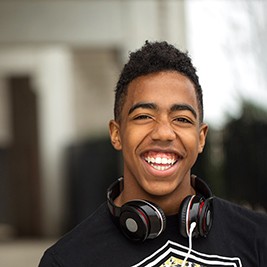 a smiling teen with headphones around his neck