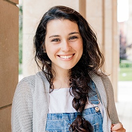 a smiling high school student leaning against a wall