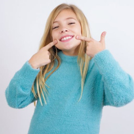 Happy child pointing at her teeth