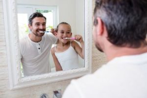 A father and daughter brushing their teeth