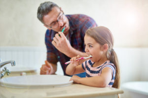 Father and daughter practicing tips about great children's dentistry 