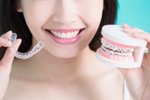 Woman holding Invisalign tray and model braces
