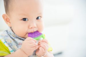 Baby using teething ring as recommended by Auburn pediatric dentist