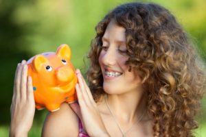 teenager holding a piggy bank for braces