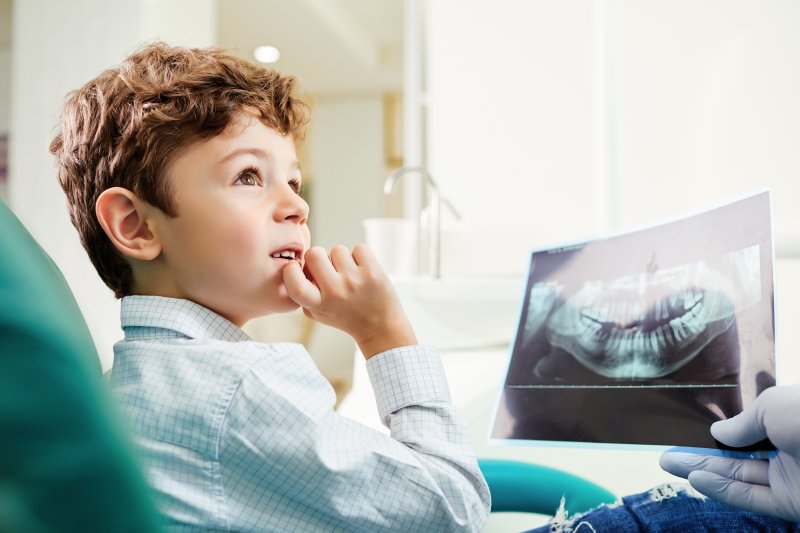 Child looking at X-ray in dentist's chair