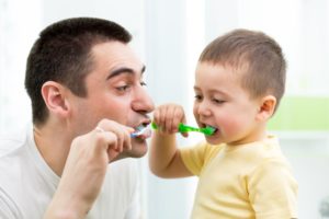 father and son brushing teeth together 