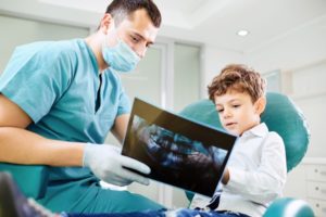 dentist showing a young boy x-rays of his mouth 