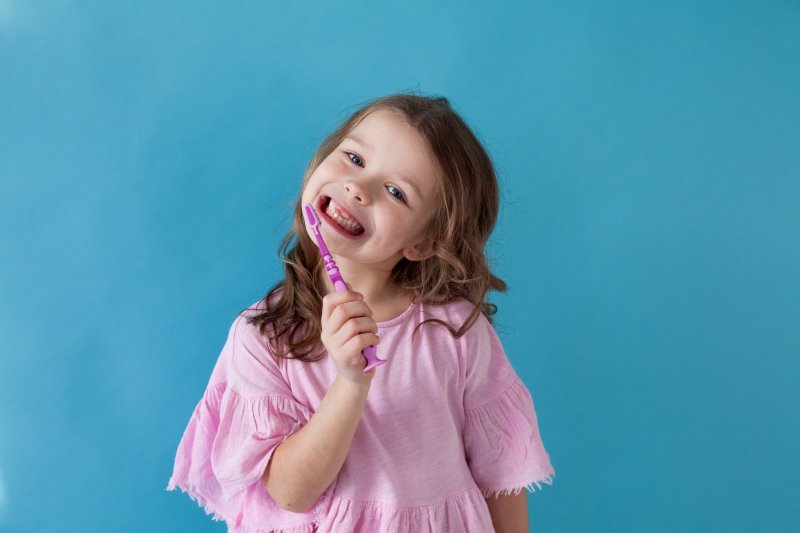 little girl smiling and brushing her teeth