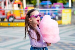 Young girl smiling and holding giant cotton candy.